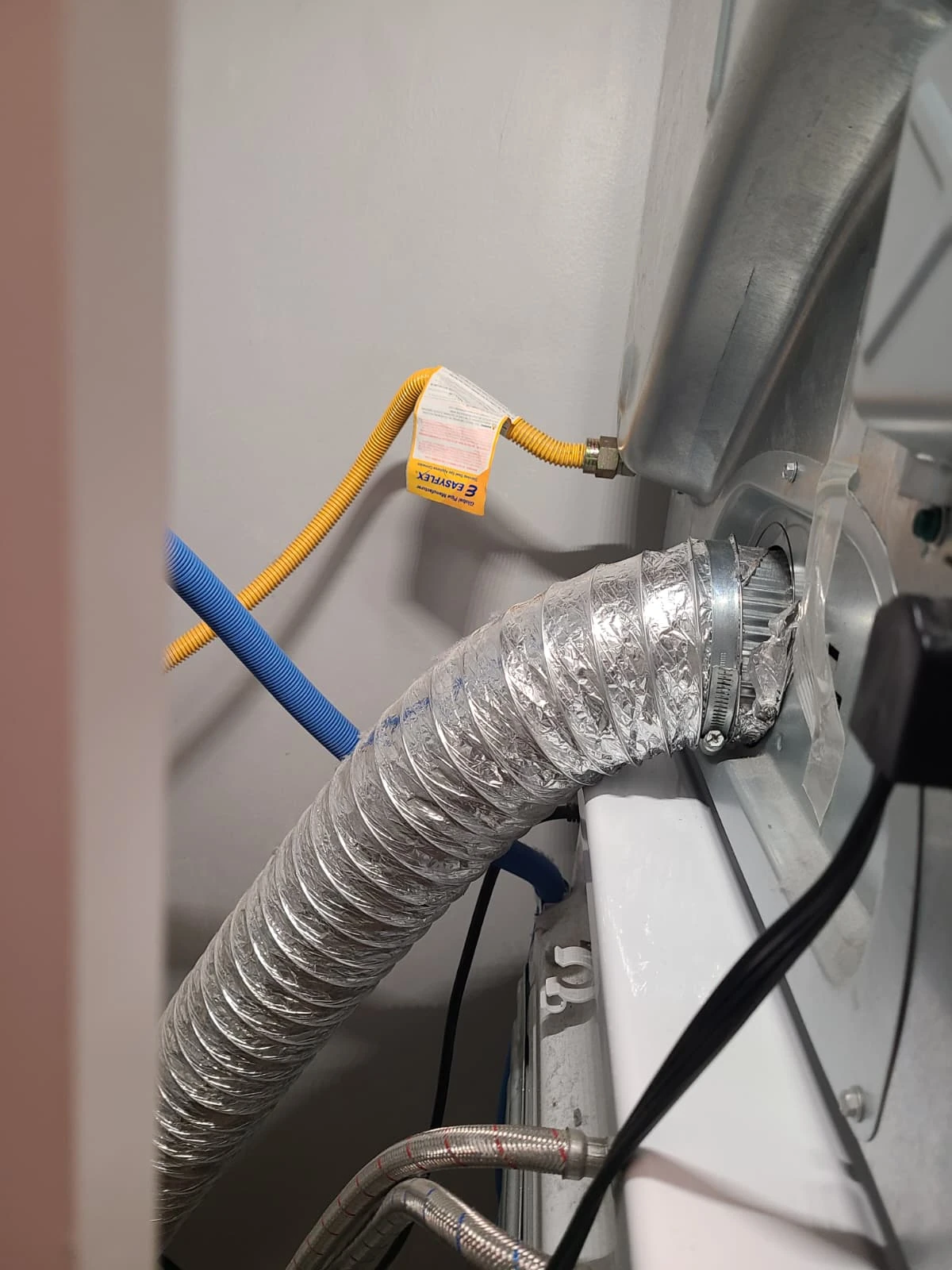 Dryer exhaust vent reconnected behind the stacked laundry pair