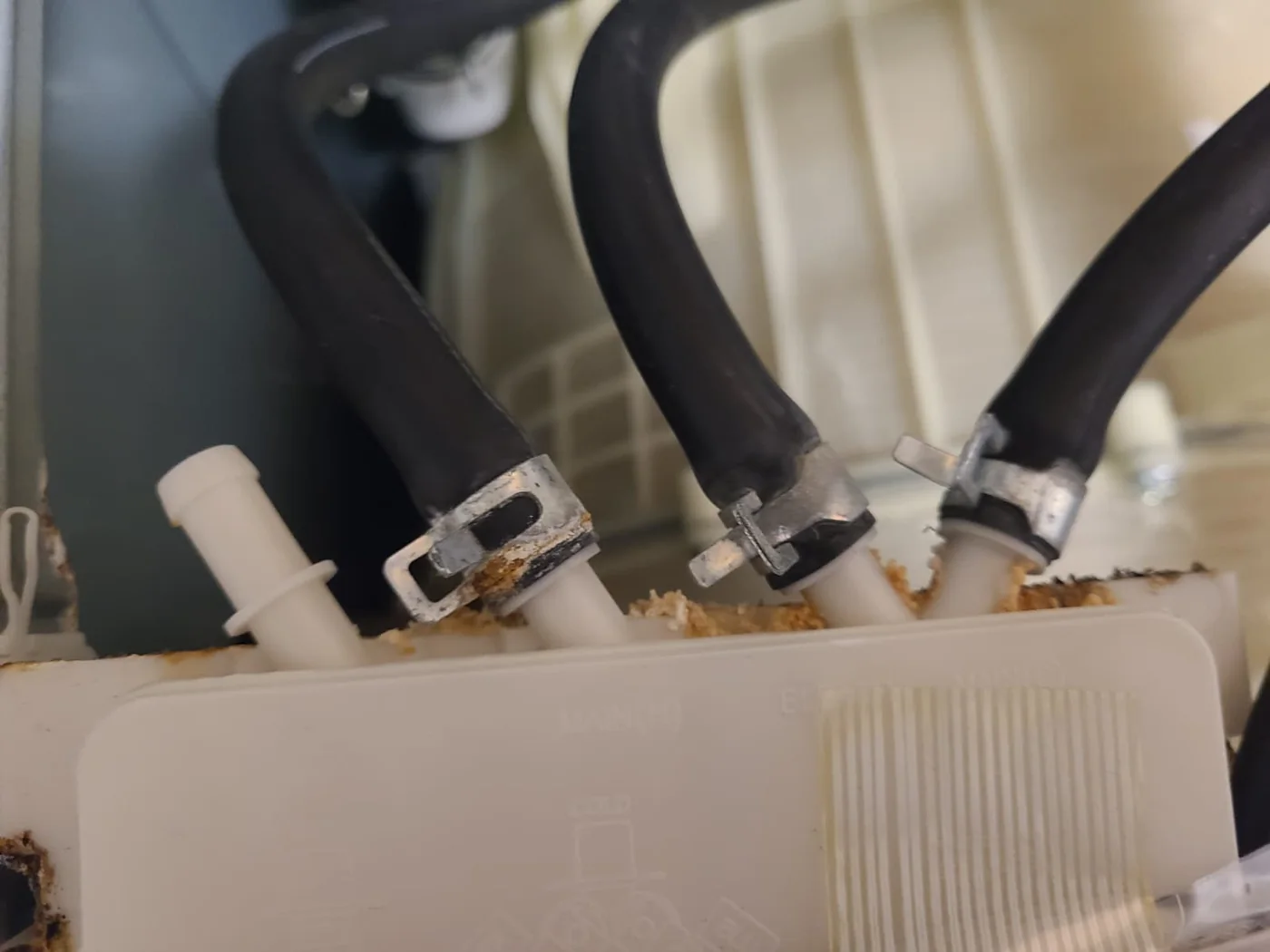 Original dispenser housing connections with visible deposits and staining around the clamps