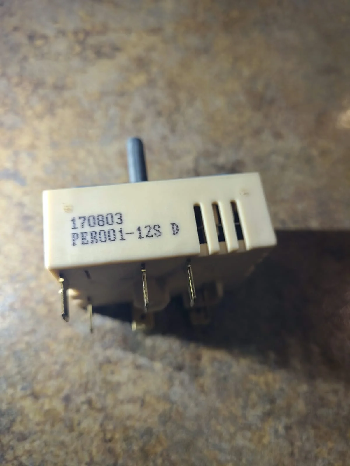 Removed burner control switch photographed on the work surface during service