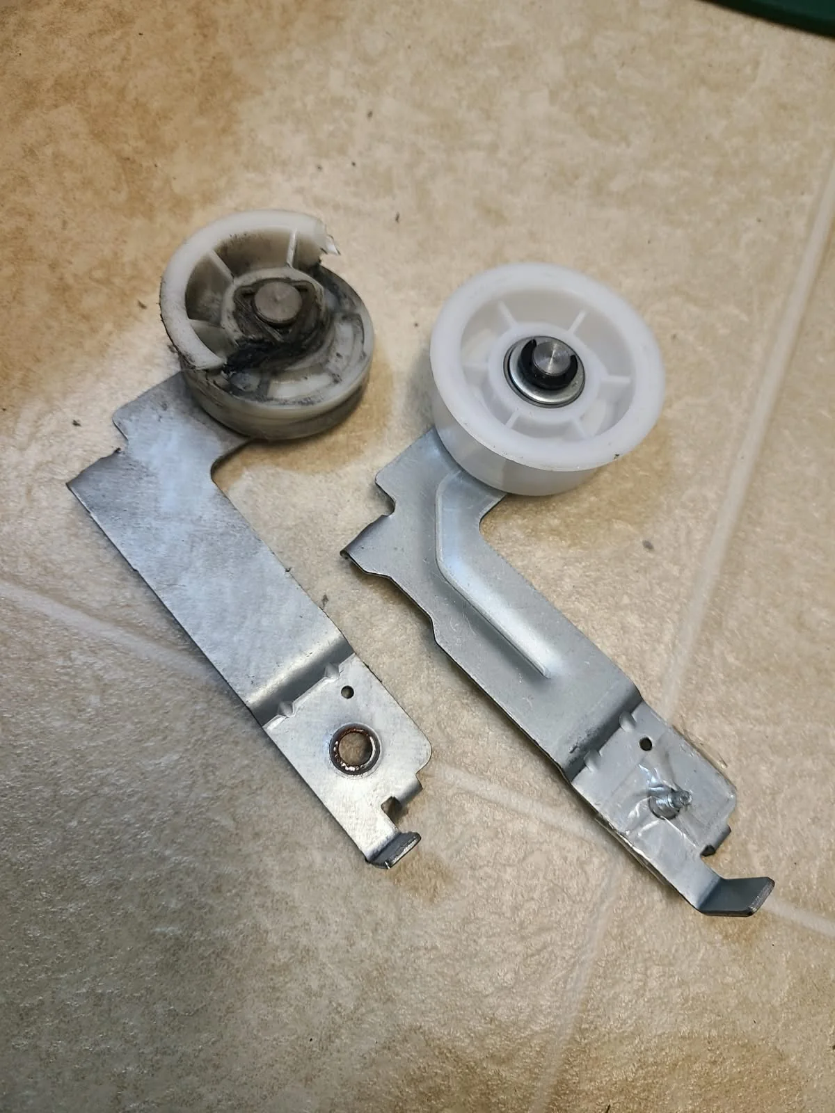 Removed damaged idler pulley assembly beside its replacement