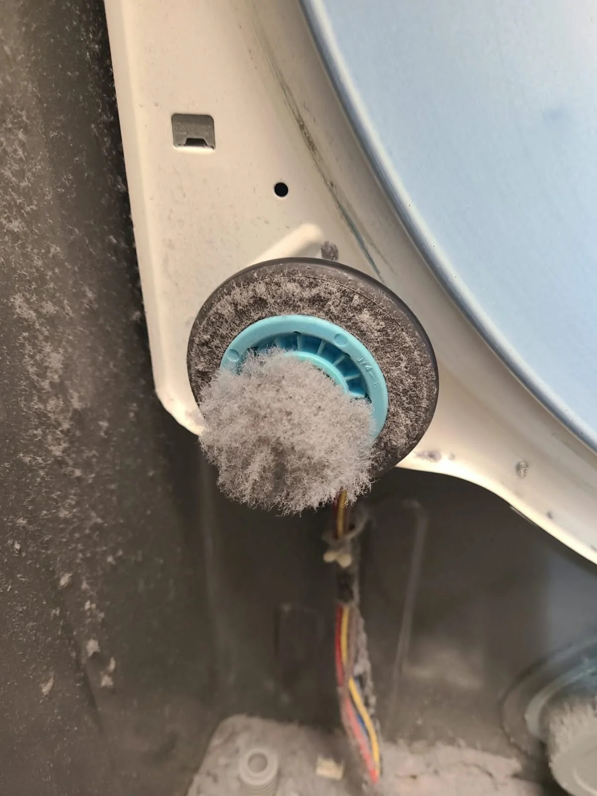 Original drum support roller covered in lint before replacement