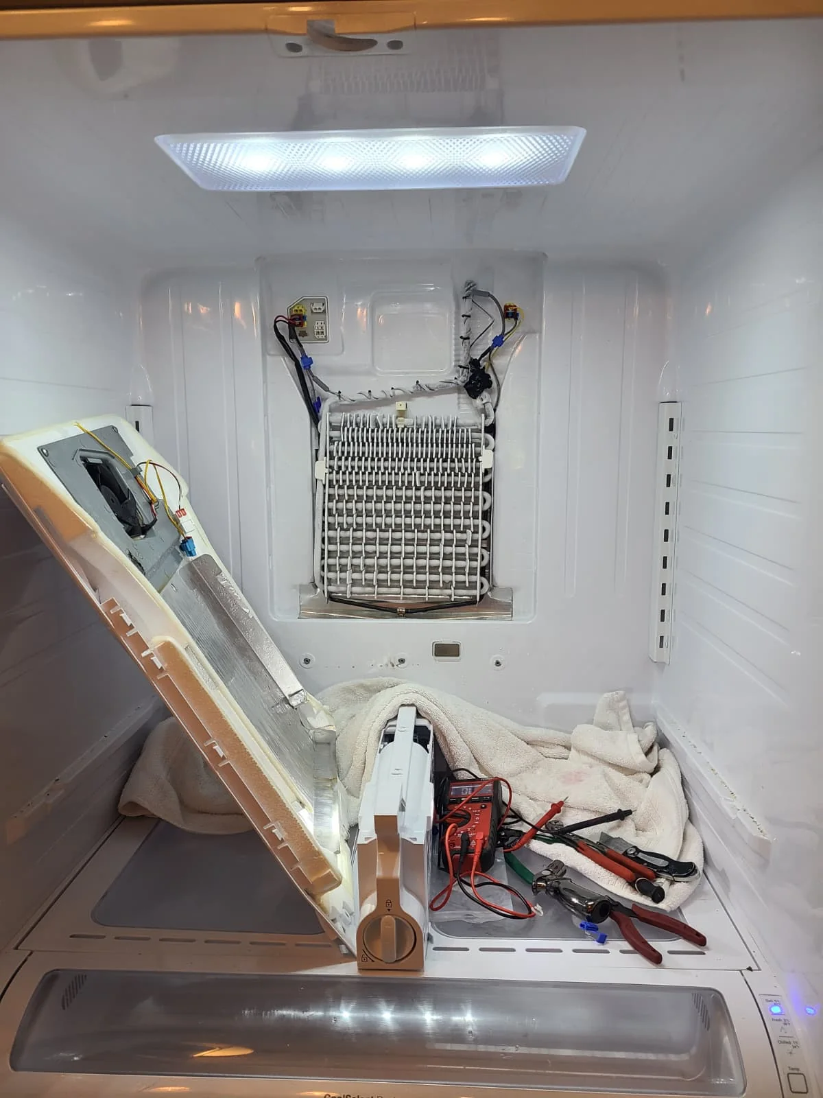 Fresh-food compartment during service with the evaporator exposed and tools on a protective towel