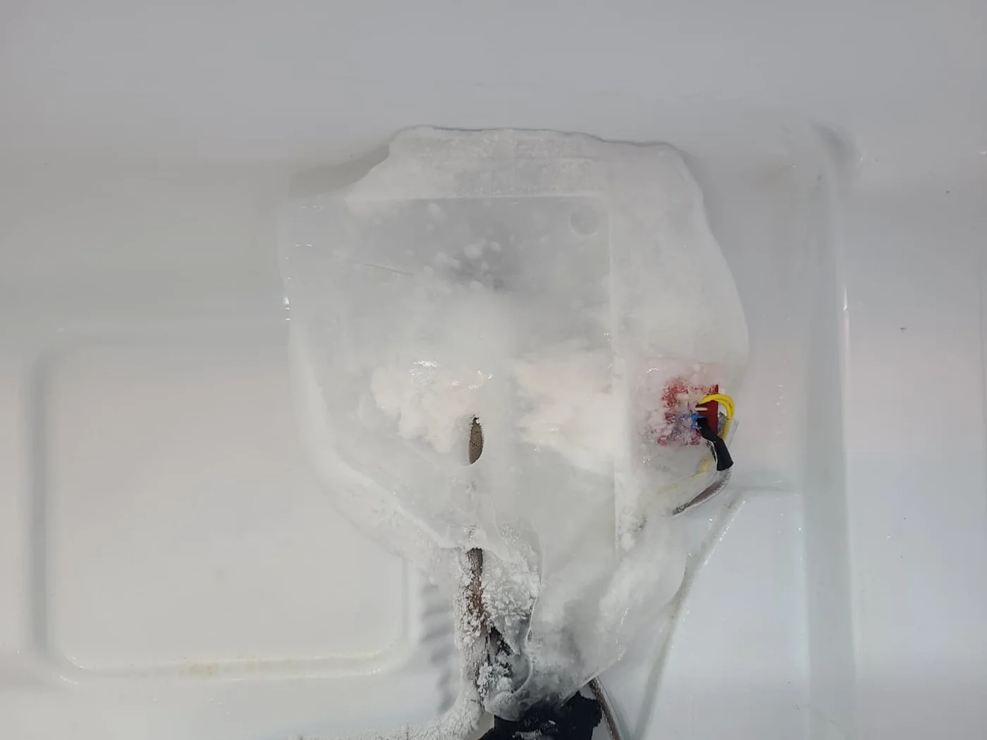Close view of the ice surrounding tubing and connections above the evaporator
