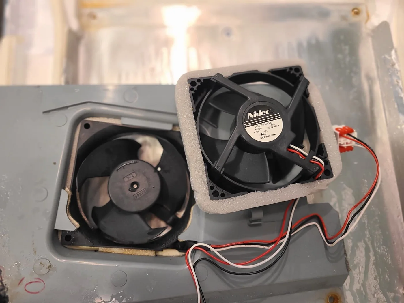 Original fan in the removed cover beside the new replacement evaporator fan