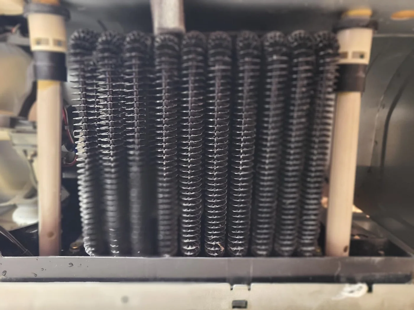 Rear drain tubes beside the condenser, accessed for removal and cleaning during this visit