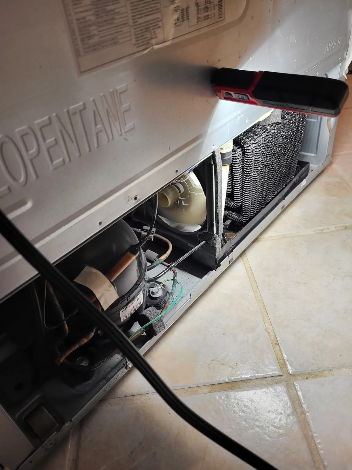 Lower rear compartment opened to access the refrigerator drain tubes